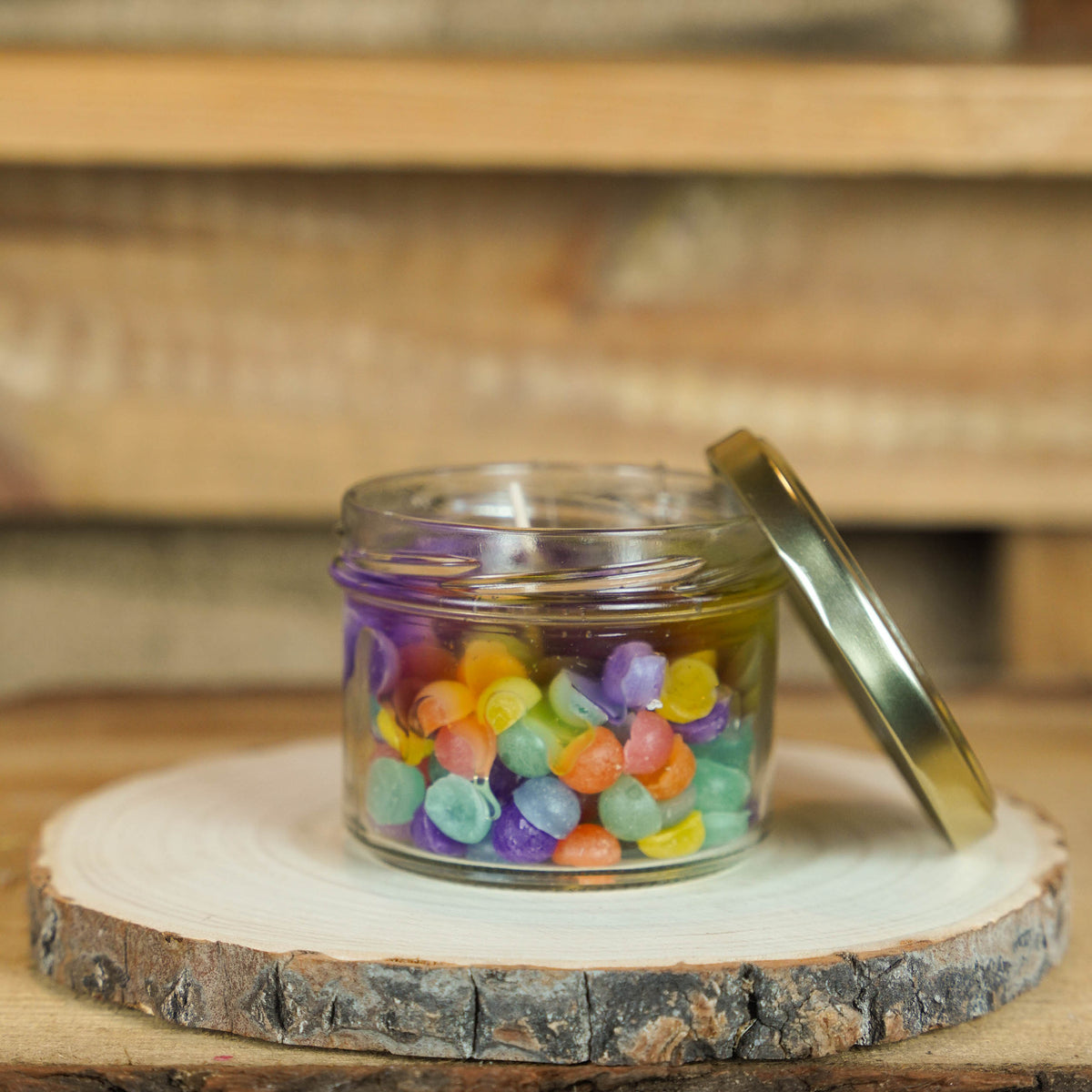 Bunte Gelkerze im Glas mit transparentem Kerzengel