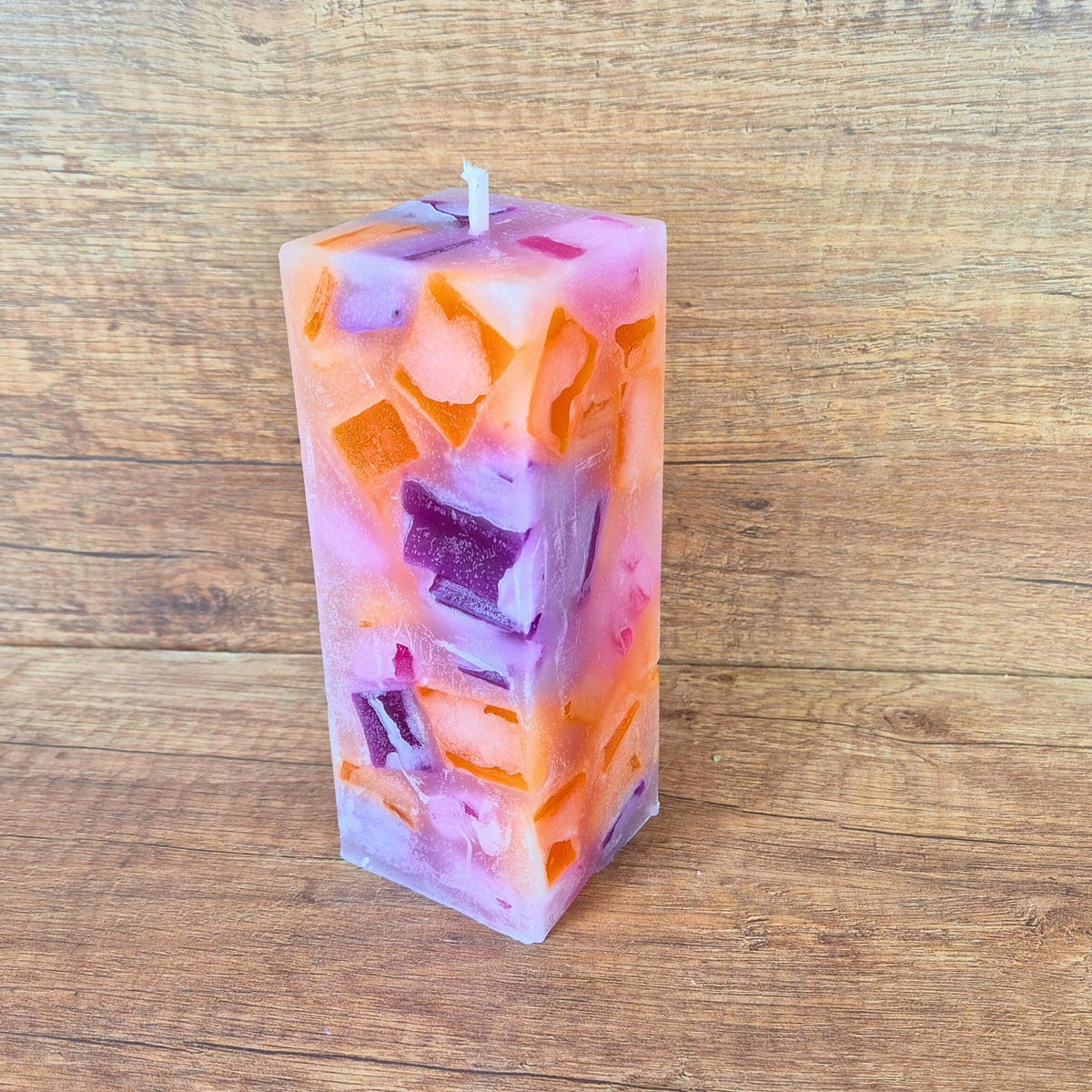 Quaderförmige Wachswürfelkerze Pink Power auf Holztisch