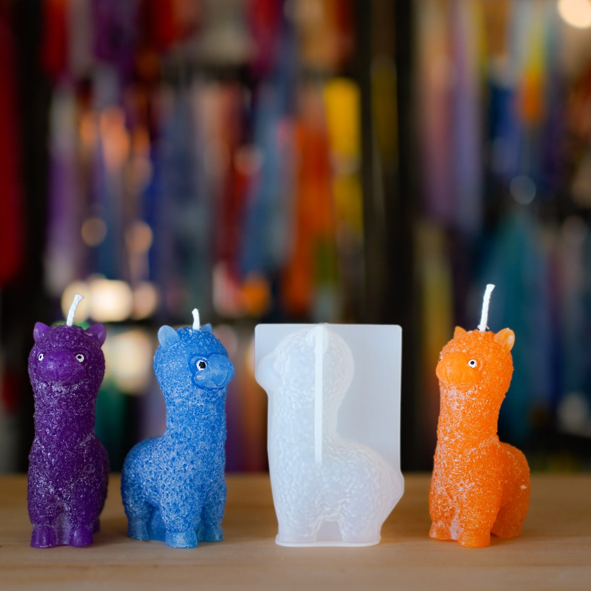 Handgemachte Alpaka-Kerzen in Violett, Blau und Orange neben der Silikonform