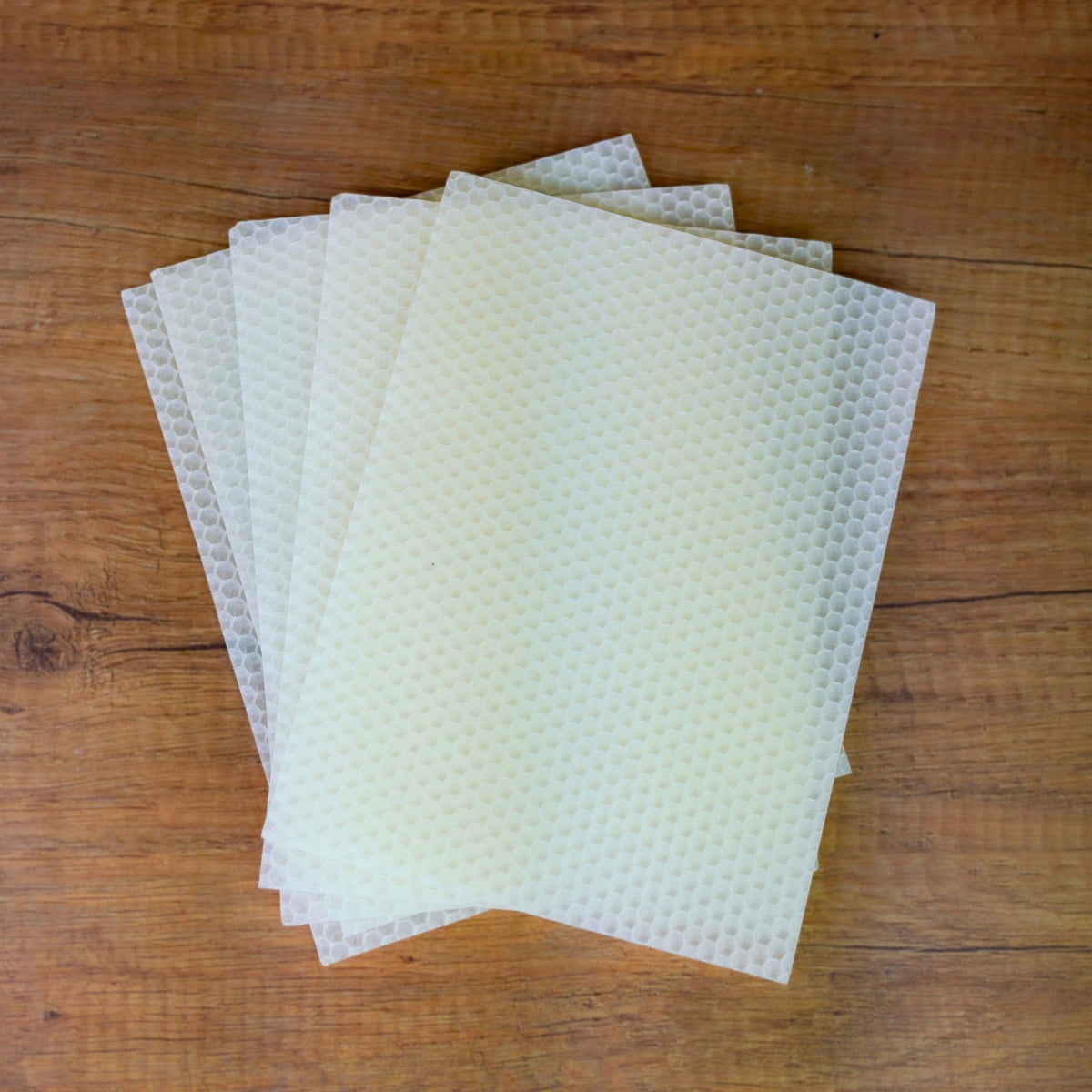 Weiße Bienenwachsplatten im 5er-Pack, aufgefächert auf rustikalem Holztisch