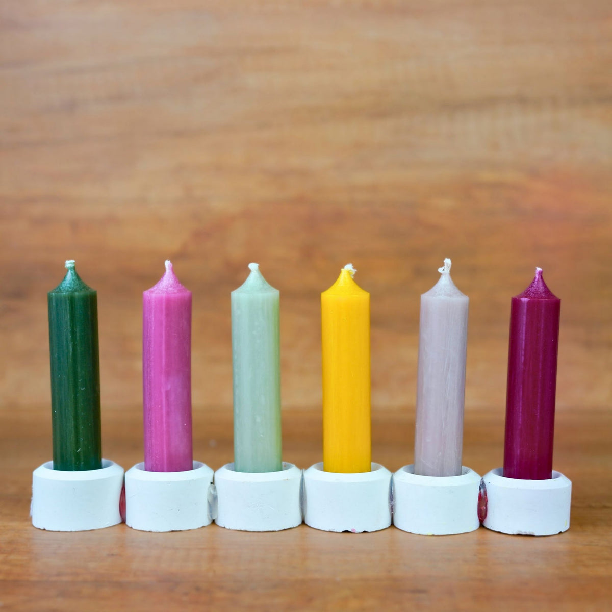 Sechs kurze Stabkerzen Gemütlichkeit in Dunkelgrün, Pink, Salbei, Gelb, Grau-Rosé und Beere, aufgereiht in Haltern