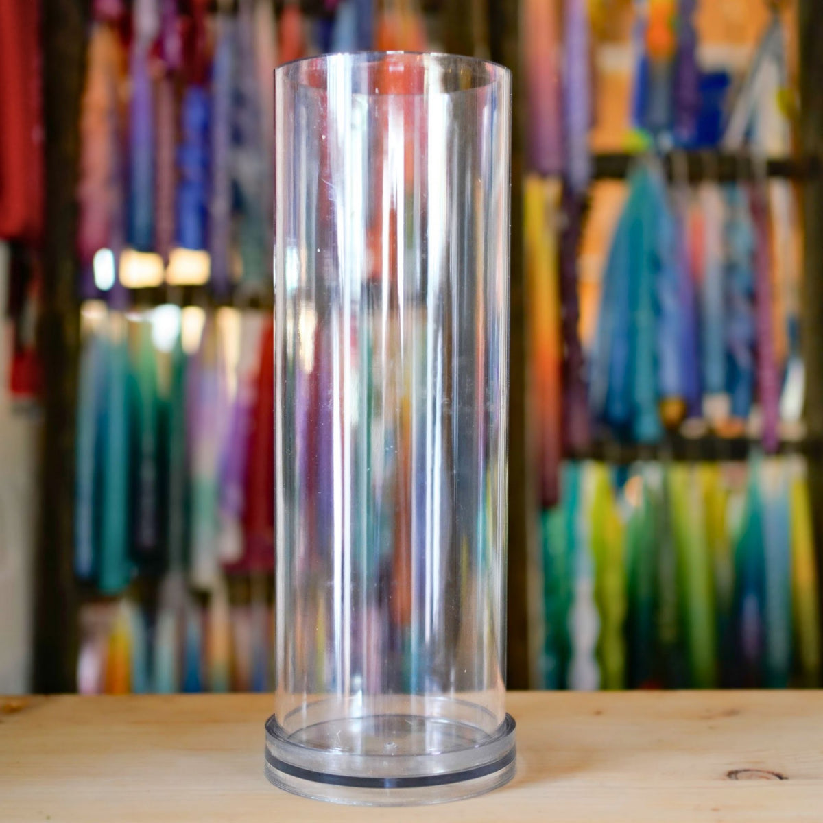 Transparente XXL Kerzengießform Zylinder 100 × 305 mm einzeln vor bunter Kerzenwand