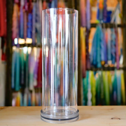 Transparente XXL Kerzengießform Zylinder 100 × 305 mm einzeln vor bunter Kerzenwand